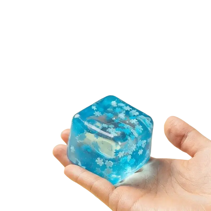 Front view of blue translucent resin snowflake ice cube stress relief toy with white floral patterns embedded