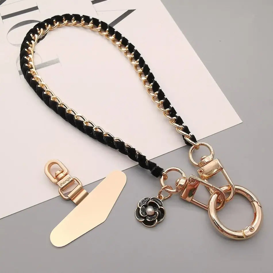 Schwarzer geflochtener Leder-Handy-Handgelenkriemen mit goldfarbenen Metallketten, floralen Anhänger-Schlüsselring und Klammerbefestigung für Anti-Lost-Handylanyard.