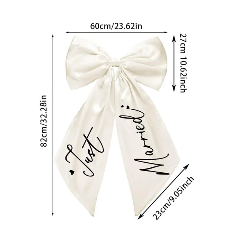 A cream satin wedding car bow featuring just married scripted in black cursive across its tails.