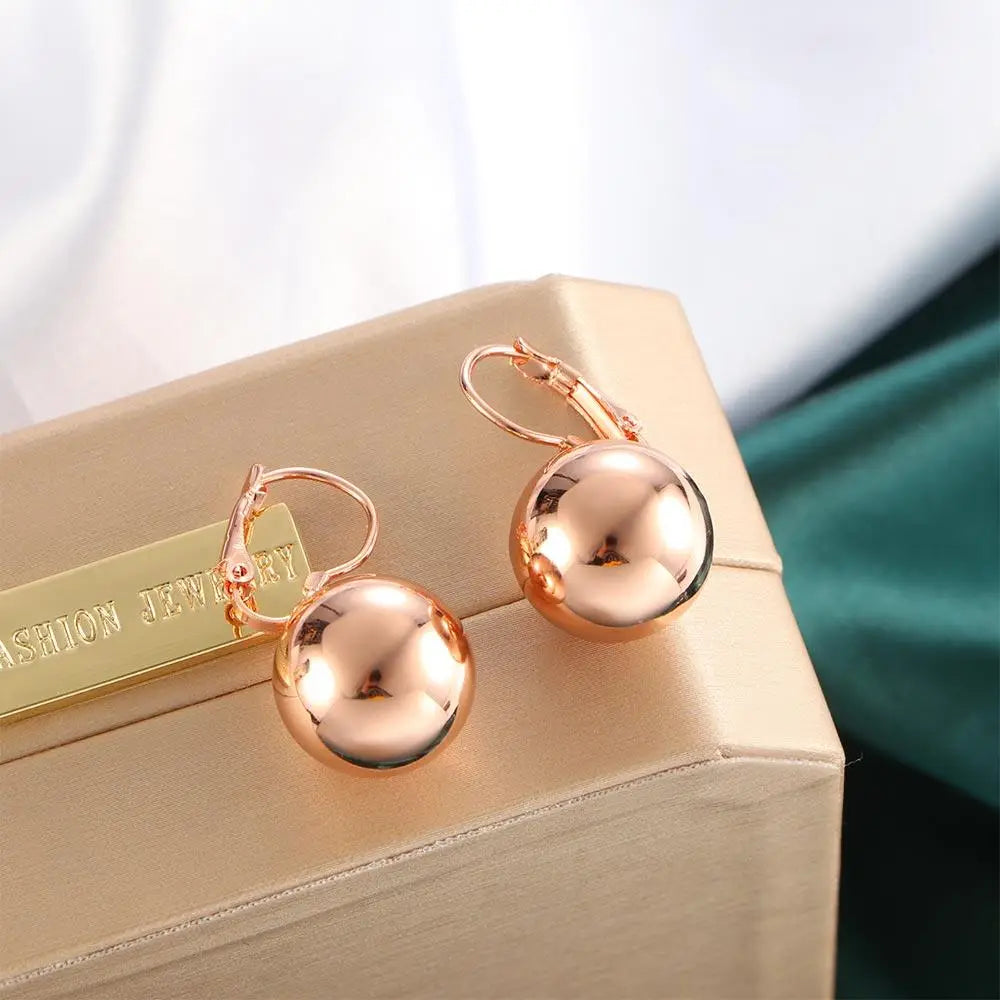 Pendientes colgantes de bola esférica en oro rosa con superficies reflectantes pulidas y cierres de palanca para un uso seguro.