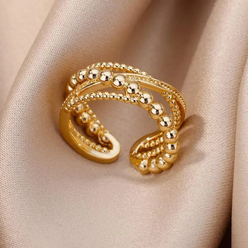 Anillos de acero inoxidable color dorado tipo, con diseño de cuentas, bandas entrelazadas en capas y una estructura abierta y delicada para joyería de boda vintage.