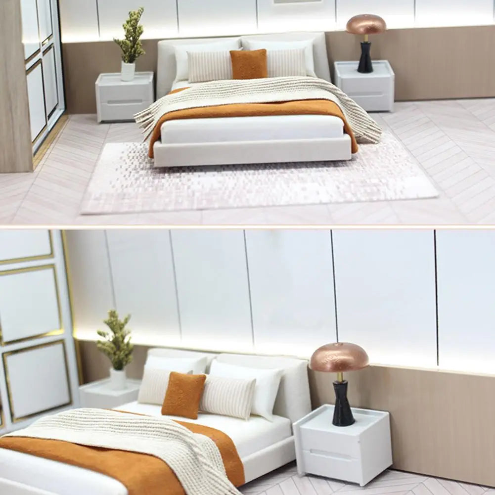 Miniature dollhouse double bed with cream white upholstered material and a sleek modern design featuring an orange throw blanket.