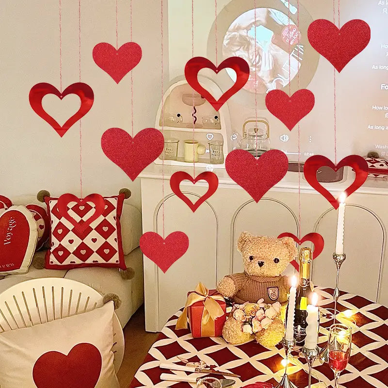 Decoraciones rojas con brillo en forma de corazón, elaboradas con material brillante, colgadas de cintas en una guirnalda para la fiesta de San Valentín.