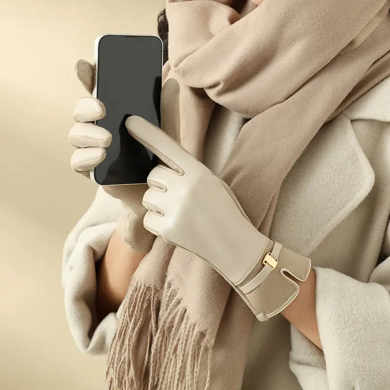 Beige Damen-Winterhandschuhe aus Leder mit einer goldfarbenen Schnalle am Handgelenk und Touchscreen-Funktion, von der Rückseite gezeigt.