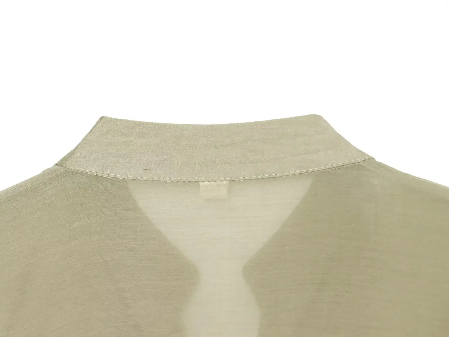 Blouse à manches longues transparente beige clair, col souplement structuré et fin surpiqûrage le long de l’encolure, idéale pour des chemises décontractées.