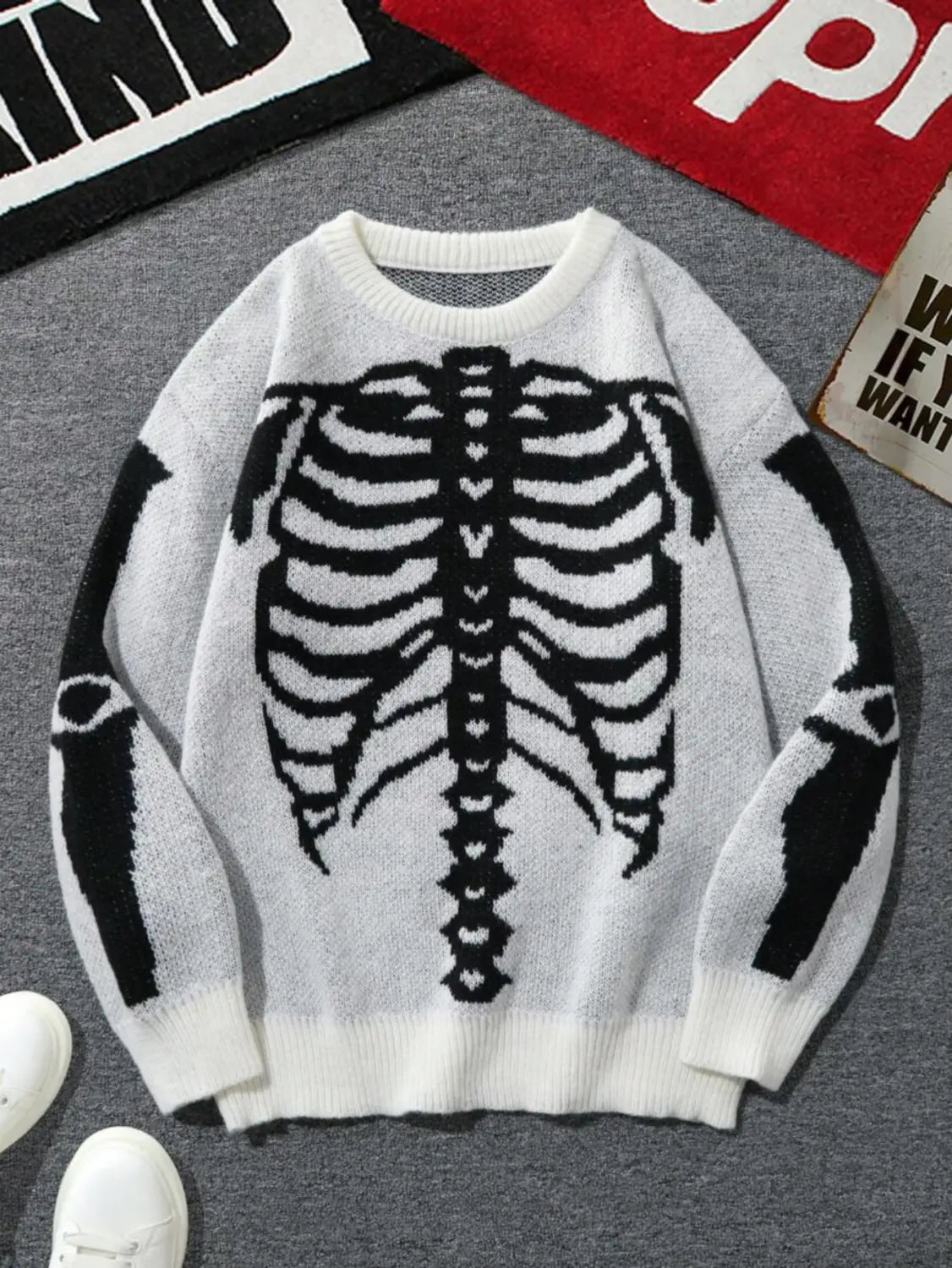 Pull gothique à jacquard squelette en maille blanc pour hommes, présentant un motif de cage thoracique noir audacieux sur l’avant et les manches.