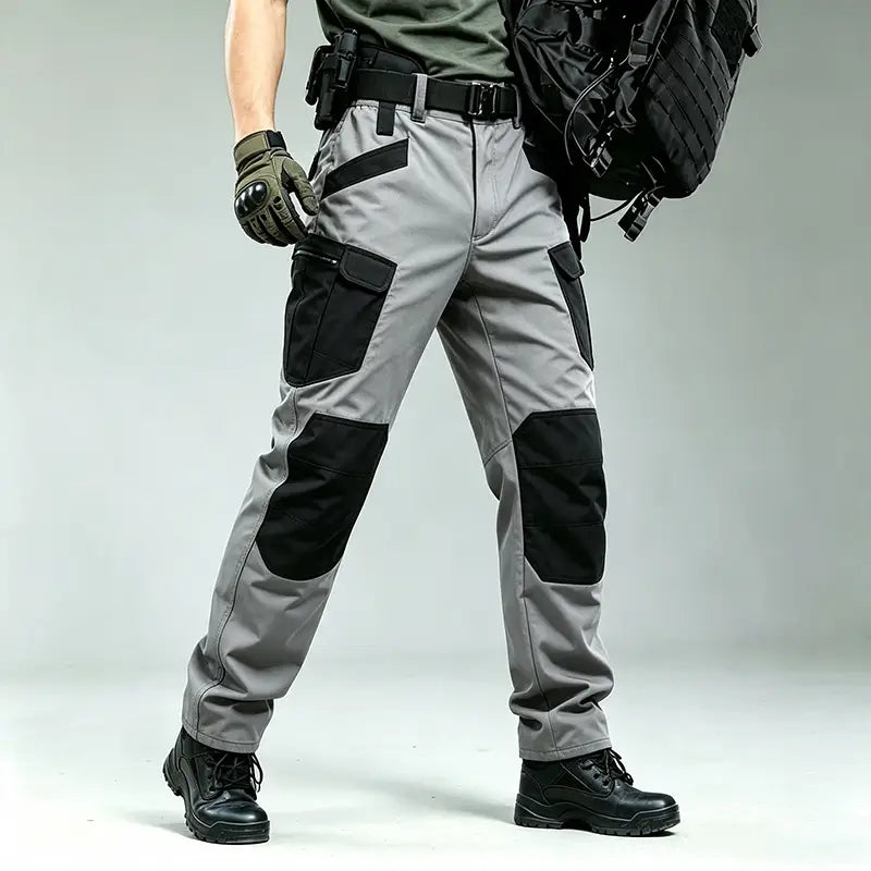Men winter tactical cargo pants in gray with black reinforced knee and thigh patches featuring multiple cargo pockets designed for waterproof hiking and outdoor use.