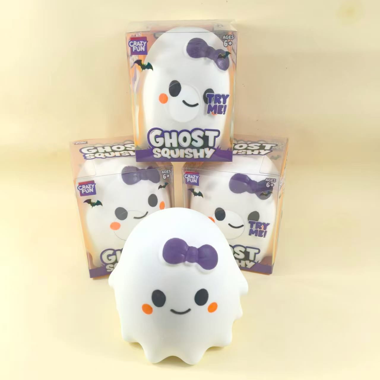 White ghost-shaped slow rising squishy stress relief toy with a purple bow, orange cheeks, and black eyes.