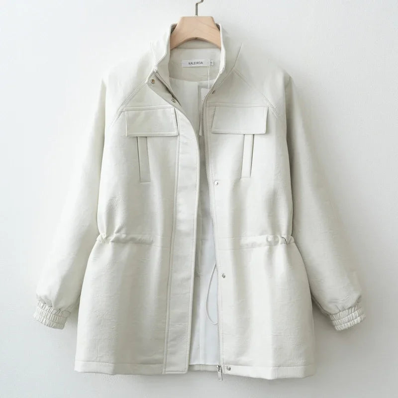 Elfenbeinfarbene, leichte Baumwolljacke mit hohem Kragen und zwei vorderen Klappentaschen, dargestellt zusammen mit einem braunen Kunstledermantel für Damen im Herbst.