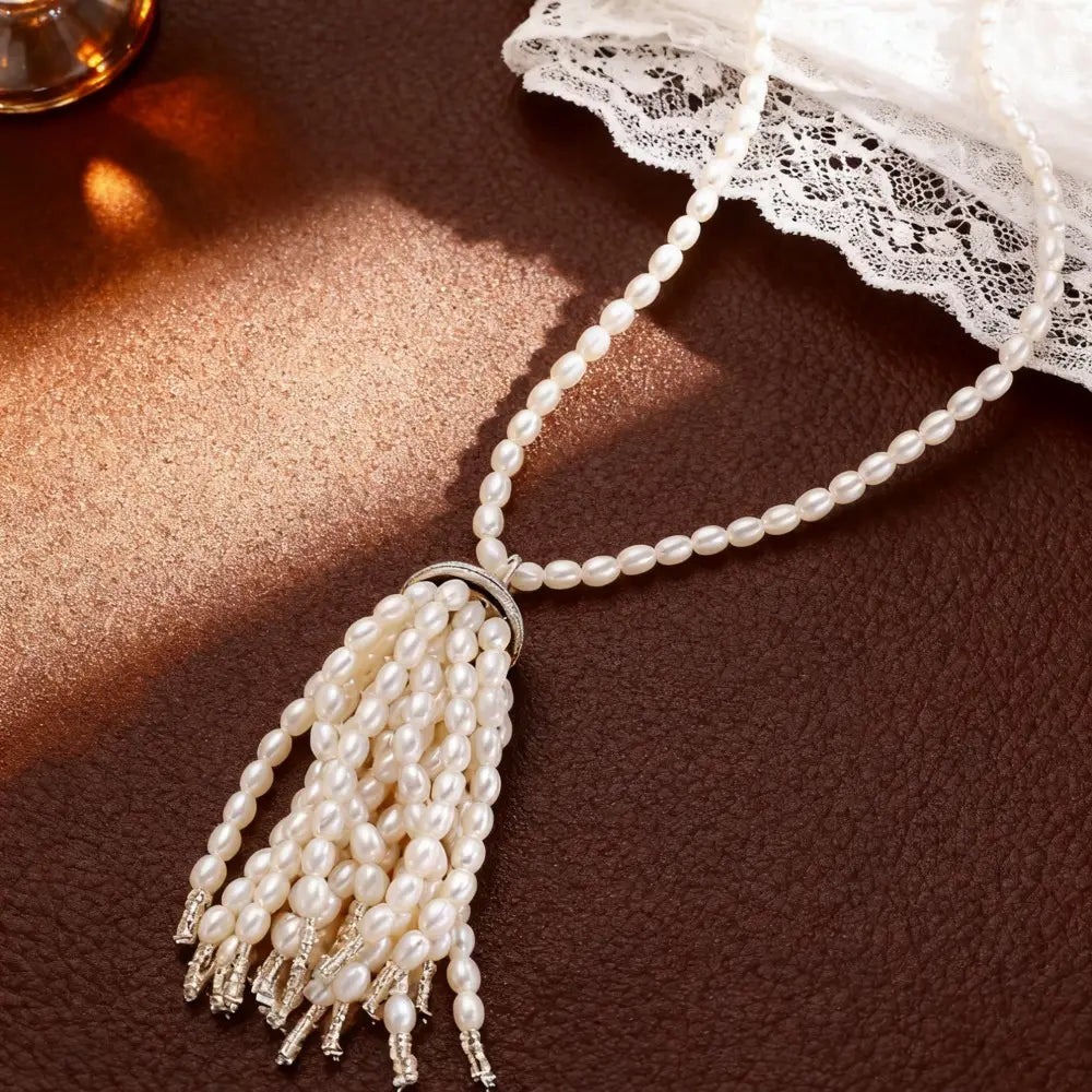 Collier-ras-de-cou élégant en perles blanches avec pendentif à pompon, fermeture à métal à ton argenté et franges délicates à perles, conçu comme une longue chaîne de pull-over.