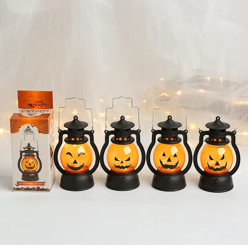 Quatre lanternes de fête d’Halloween en métal noir avec des visages de jack o’lantern orange lumineux en plastique, pour la décoration de fête d’Halloween.