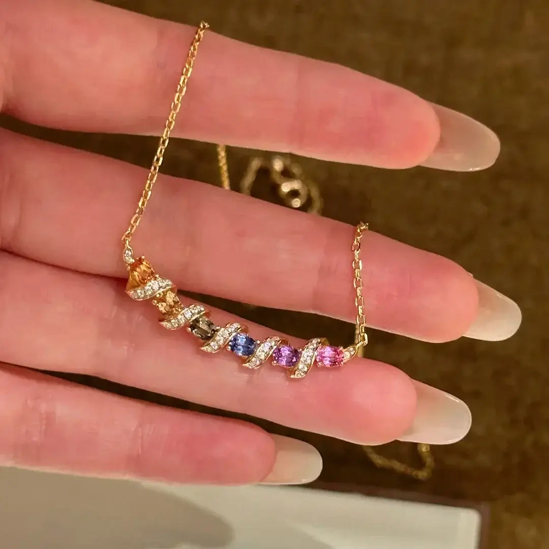 Un collier en argent, avec une chaînette délicate en or, un design torsadé coloré et un pendentif multigemme éclatant en orange, bleu, violet et rose.