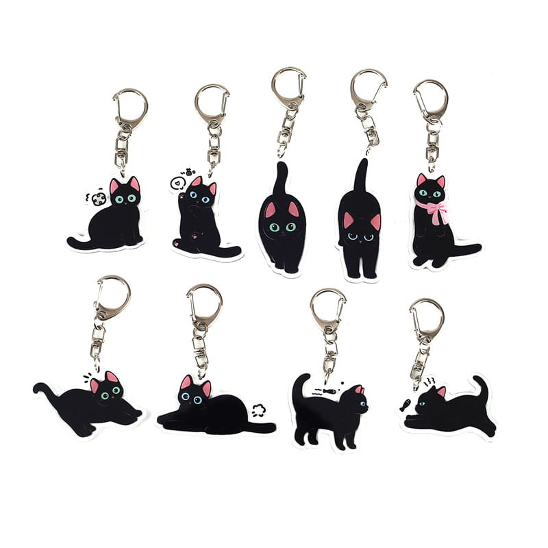 Set of ten black cat acrylic keychains with pink inner ears and green eyes featuring different poses and expressions for use as cartoon animal bag charms.
