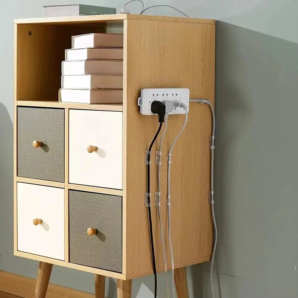 White wall-mounted power strip with multiple outlets and neatly bundled cords held by cable organizer clips for desktop cord management.