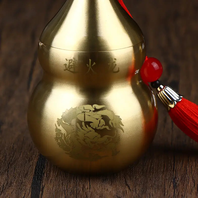 brass gourd feng shui prosperity ornament in golden metallic finish with engraved chinese characters and dragon design adorned with a red tassel