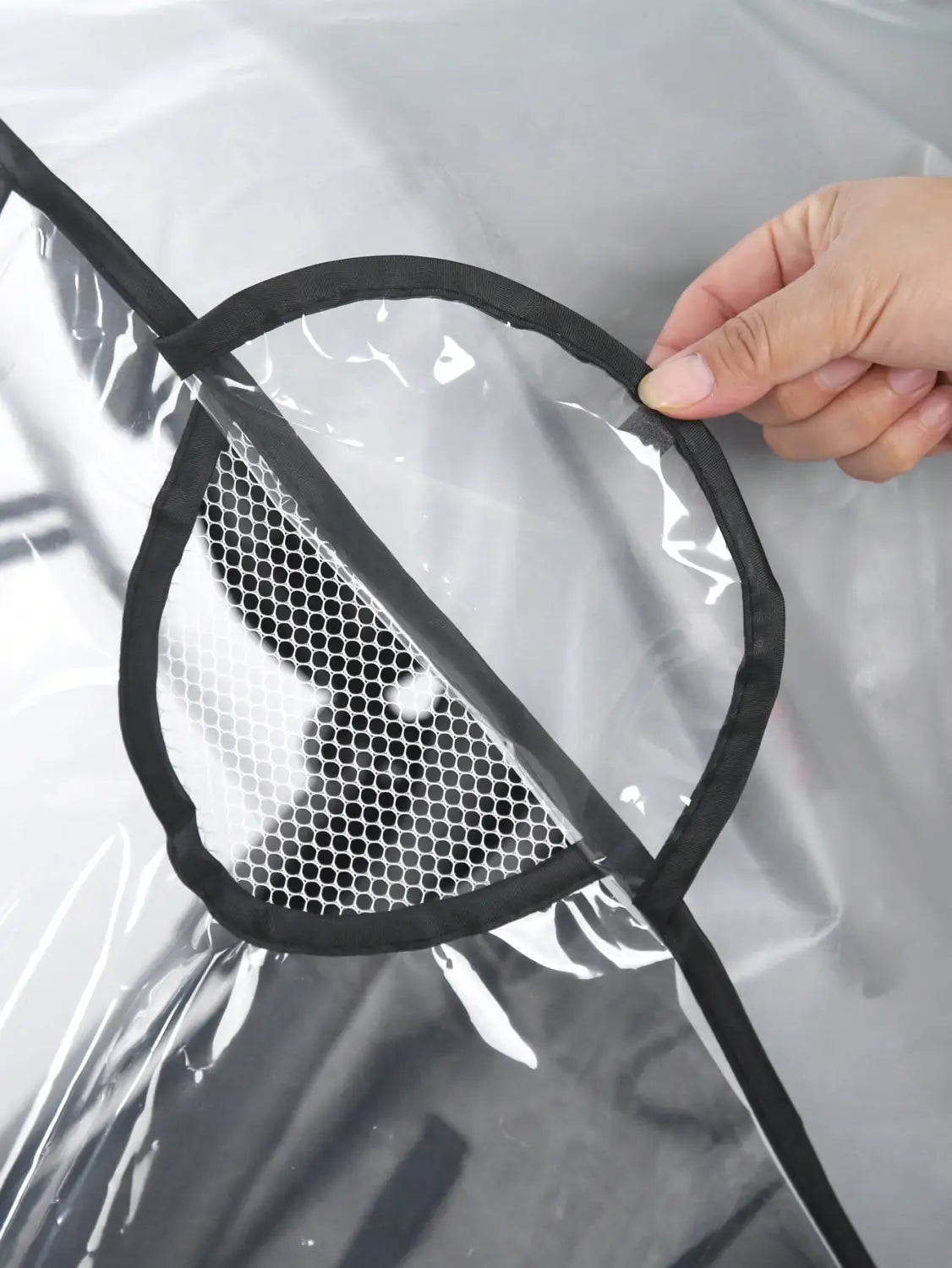 Klare Kunststoff-Regenschutzjacke mit schwarzem Besatz und rundem Mesh-Taschenfach, gestaltet als universelle transparente Regenschutzabdeckung für Kinderwagen.