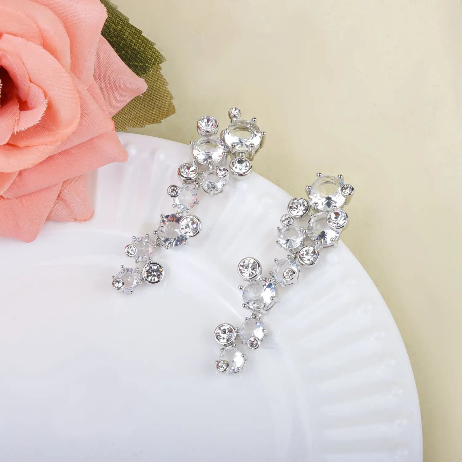 Une paire de boucles d’oreilles pendantes dégradées ton argent, ornées de cristaux facettés transparents, issues d’un ensemble de bijoux de mariage en cristal comprenant un collier en argent et des boucles d’oreilles.