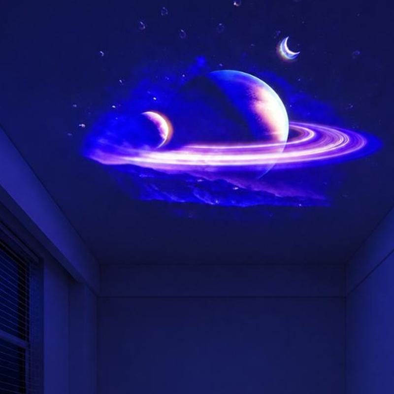 Proyector de galaxia USB con decoración vibrante de techo cósmico en azul y morado, con un planeta central que presenta anillos luminosos, lunas en forma de creciente y estrellas dispersas mediante discos de proyección reemplazables