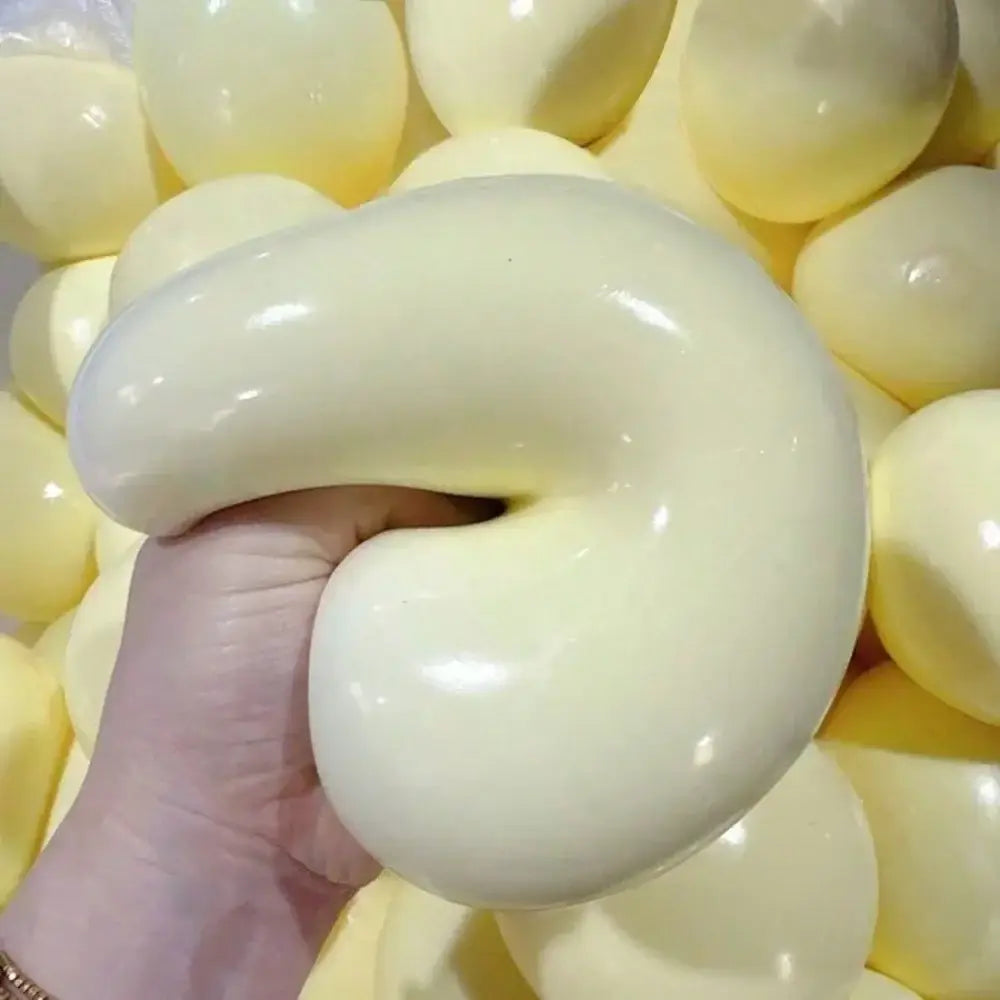 una pelota blanda y esponjosa de color amarillo pálido con un diseño brillante en forma de U para aliviar el estrés, vista desde el frente