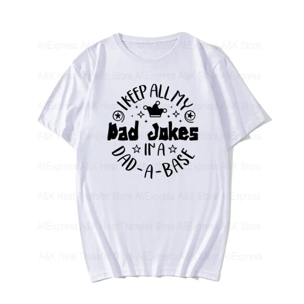 ダッドジョークのヒートトランスファーアイロン貼りパッチ付き、黒文字のプリントTシャツ。『i keep all my bad jokes in a dad-a-base』と表示されたテキストを、星と王冠に囲まれたデザインであしらっています。