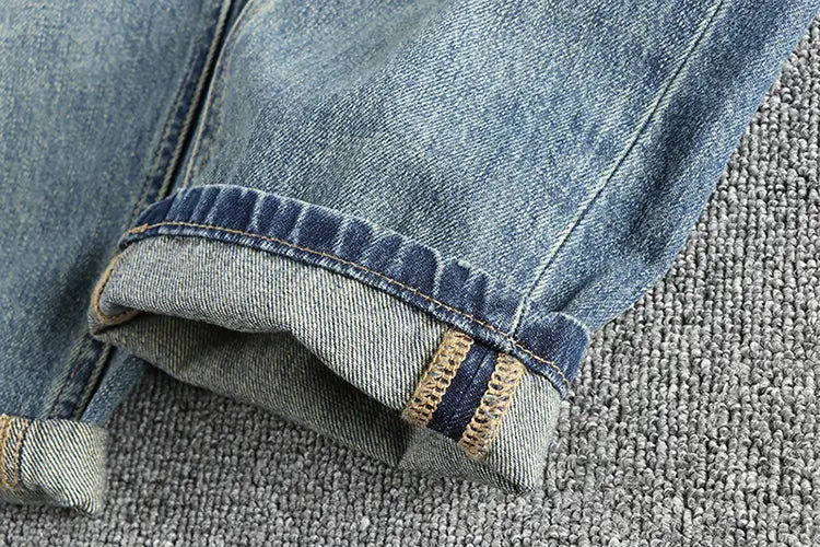 Jeans en denim ample à broder pour hommes en bleu, avec des revers retroussés et des coutures contrastantes ton tan.