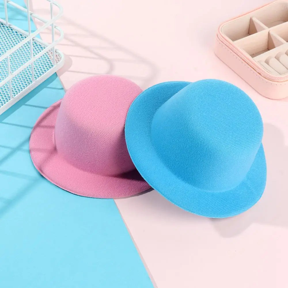 Une paire de chapeaux melon (bowler) en feutre doux en rose pastel et bleu, conçus comme accessoires de mode pour chapeau de poupée en peluche pour des poupées de 60 cm.