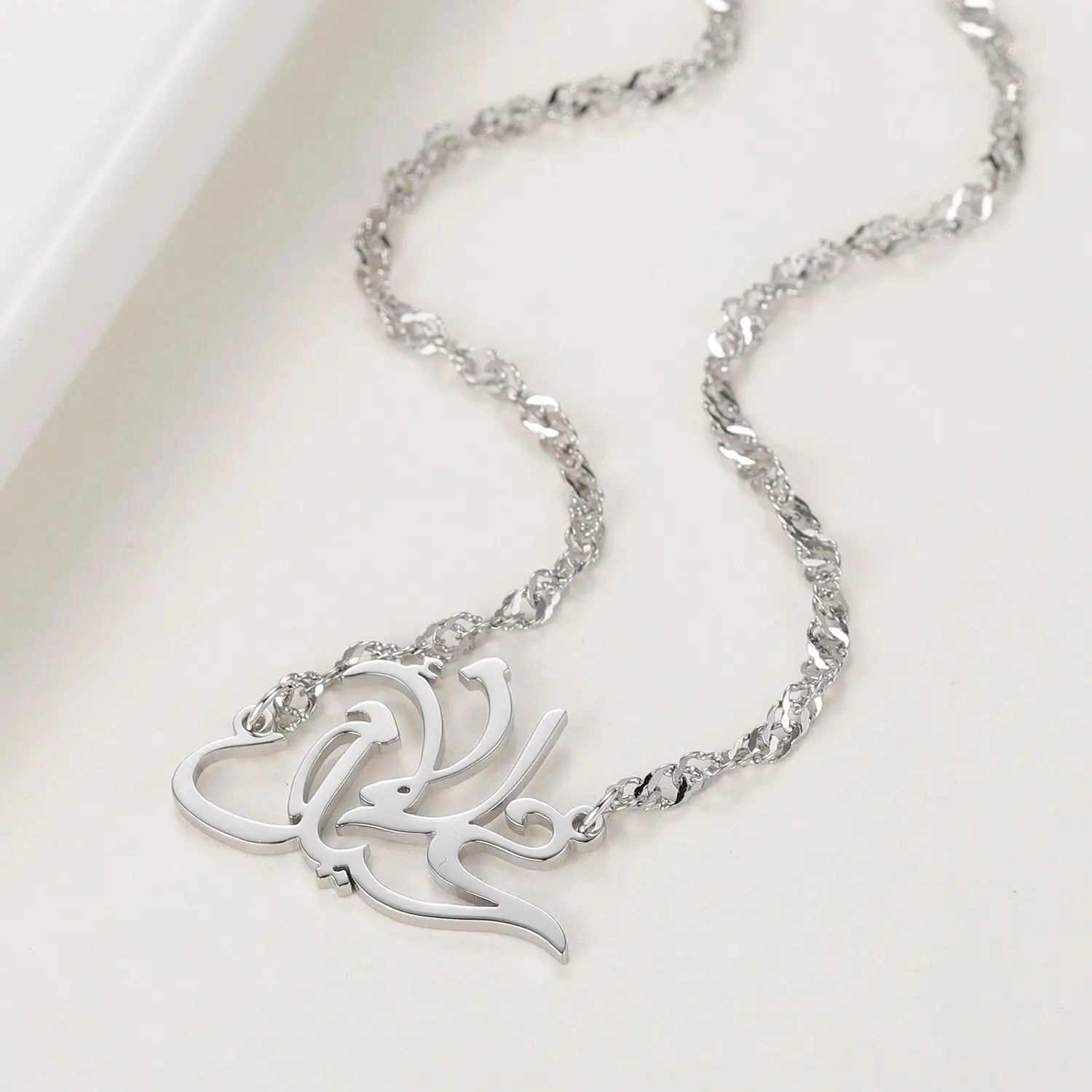 Silver chain necklace featuring an intricate heart-shaped pendant with elegant arabic calligraphy in gold plated personalized arabic name necklace design.