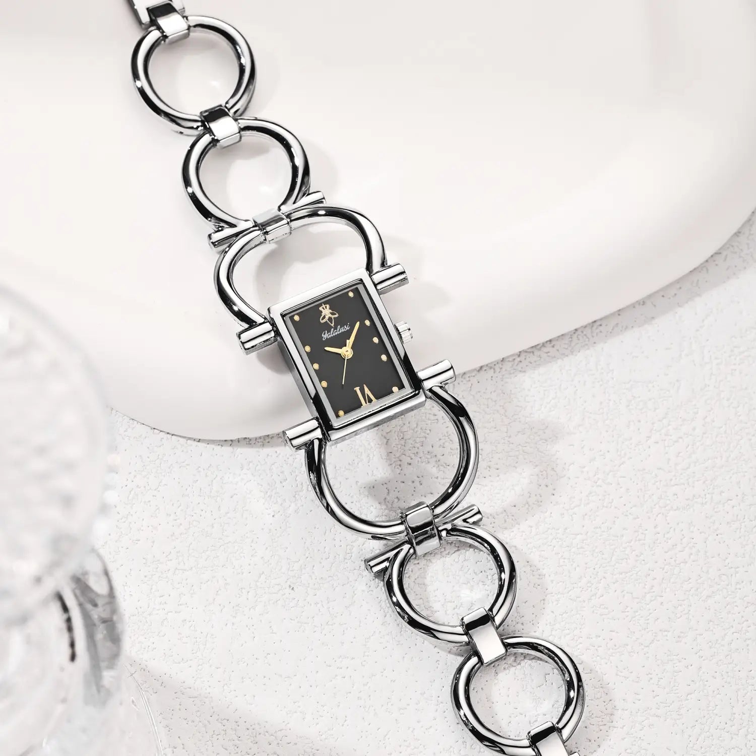 Gold luxury quartz women watch bracelet featuring a silver-toned rectangular case with a black dial, gold-tone hands, and roman numeral hour markers.