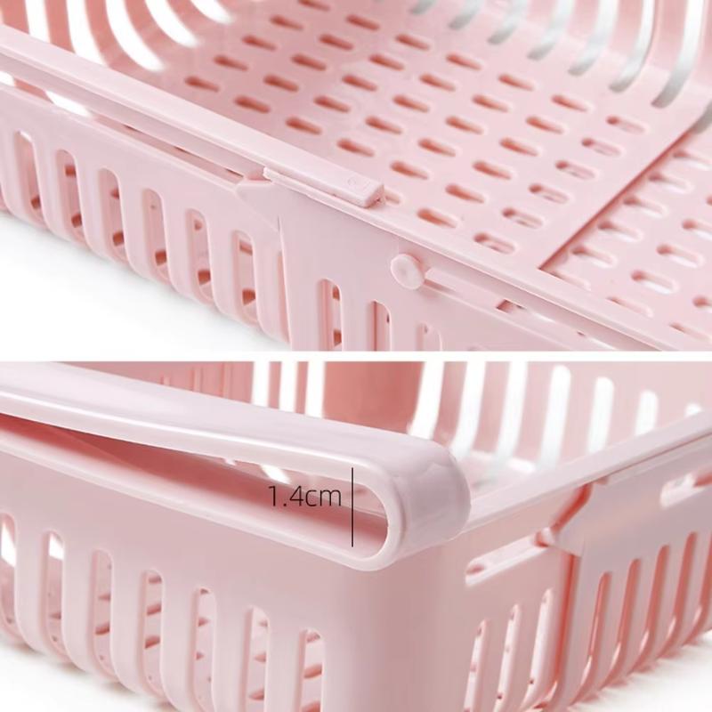pink plastic sink drain rack with perforated design and integrated handle made of food-grade polypropylene for adjustable kitchen shelf use.