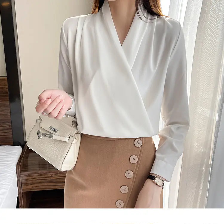 Vネックラインと長袖を備えた、女性向けの洗練されたオフホワイトサテンのブラウス。
