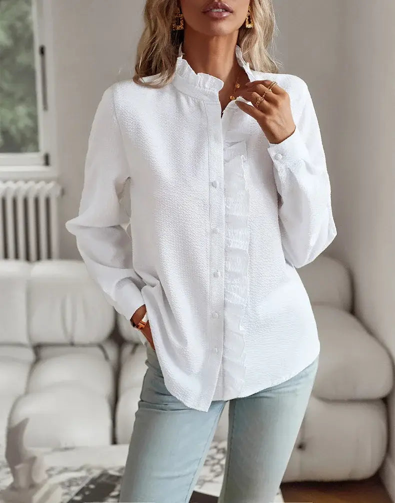 Blusa blanca de textura con manga larga, cuello con volantes y parte delantera abotonada, confeccionada con tejido ligero.