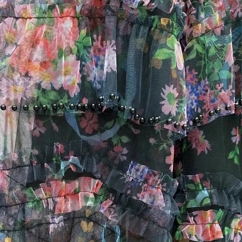 Una falda de tul floral translúcida en capas, con volantes escalonados y ribete de perlas negras engastadas en estilo fairycore Y2k.