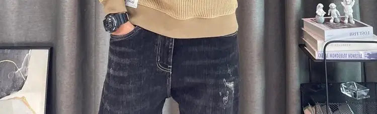 Jean en denim à lavage foncé avec détails délavés et surpiqûres blanches, associé à un pull-over en maille à empiècement contrastant pour homme, manches longues.