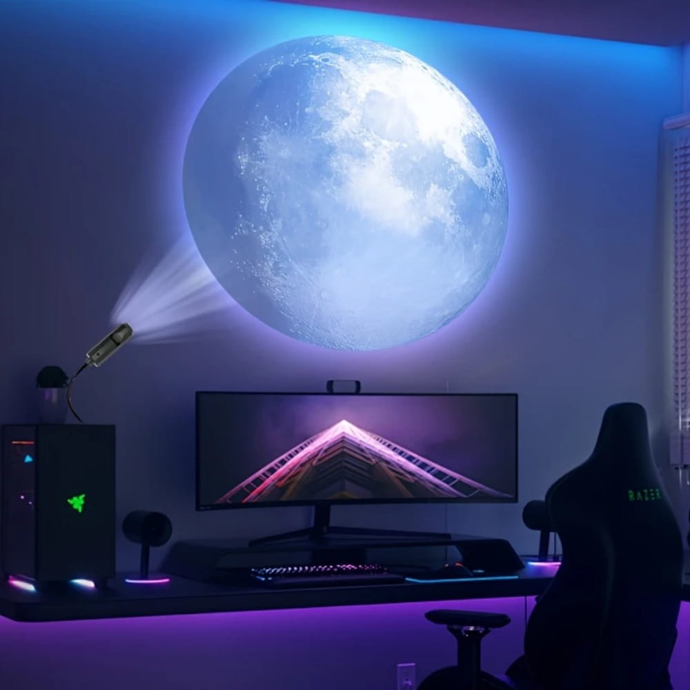 Gaming setup featuring a galaxy projector led night light with a glowing blue moon wall light above the monitor and rgb-lit peripherals with a Razer gaming chair.