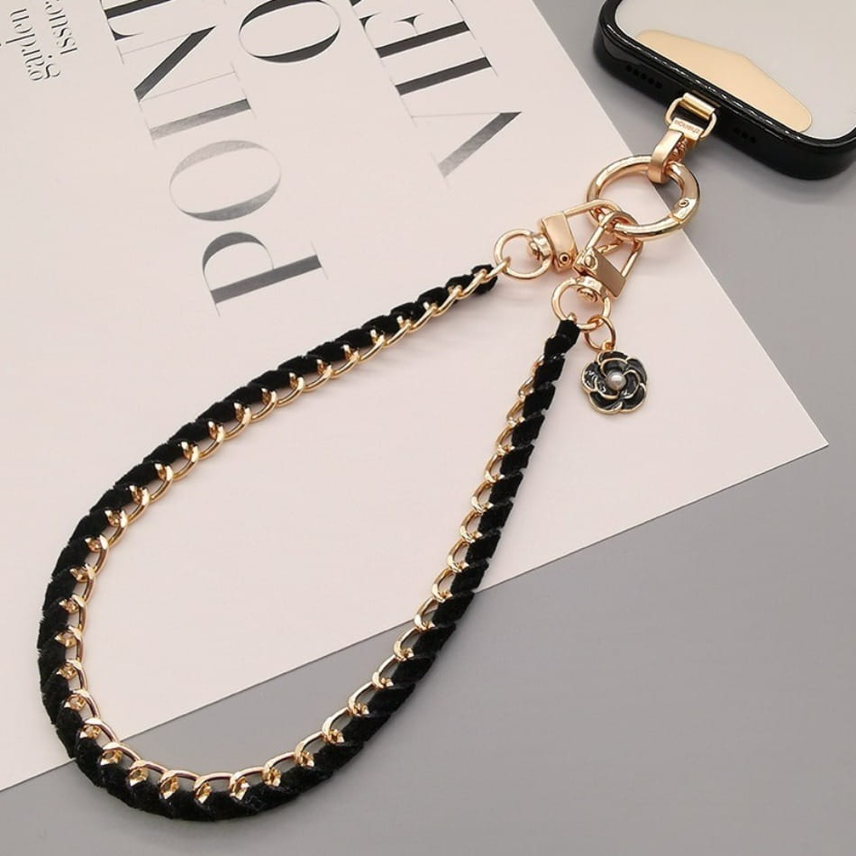 Schwarzer geflochtener Kord-Handy-Handgelenkriemen mit goldfarbenen Kettengliedern und einem floralen Anhänger, entworfen als Anti-Lost-Handylanyard.