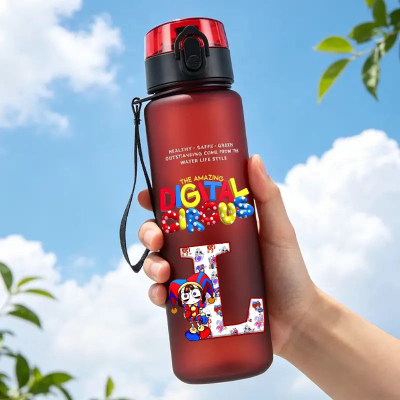 A translucent red digital circus water bottle with a black and red screw-on lid featuring colorful lettering and a cartoon character design on its side.