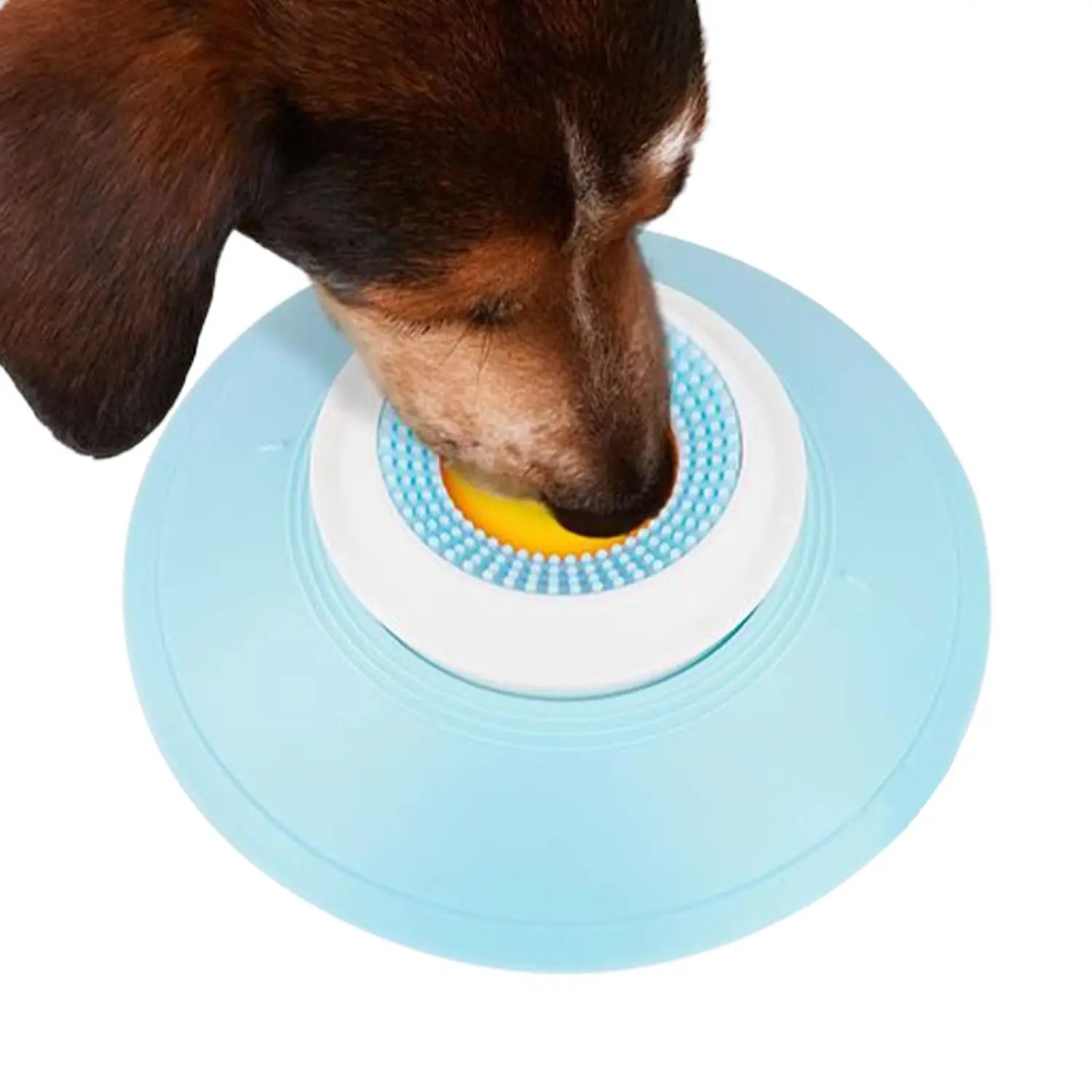 明るい青色の円形の犬用リックトイで、白色の内側リングと、黄色の中心を囲む質感のある青色のブラシがあり、インタラクティブなスローフィーダーボールとして設計されています。