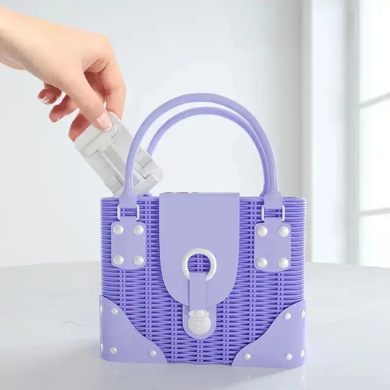 Support réglable pour téléphone de bureau et tablette en argent, avec un sac à main en plastique tissé couleur lavande, agrémenté de rivets blancs et d’une serrure assortie.