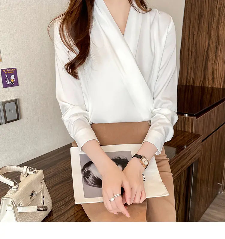 洗練されたエレガントなスタイル向けにデザインされた、女性用の長袖とVネックラインの白いサテンブラウス。