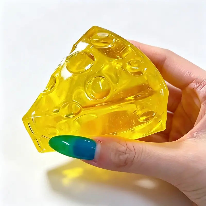 a translucent yellow soft mini triangle cheese fidget stress relief squeeze toy with embedded circular holes resembling a cheese fidget toy