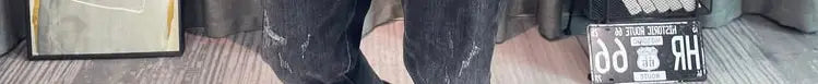 Jean en denim noir déchiré avec lavage délavé et motifs d’usure visibles, associé à un pull-over en maille à empiècement contrastant pour homme, manches longues