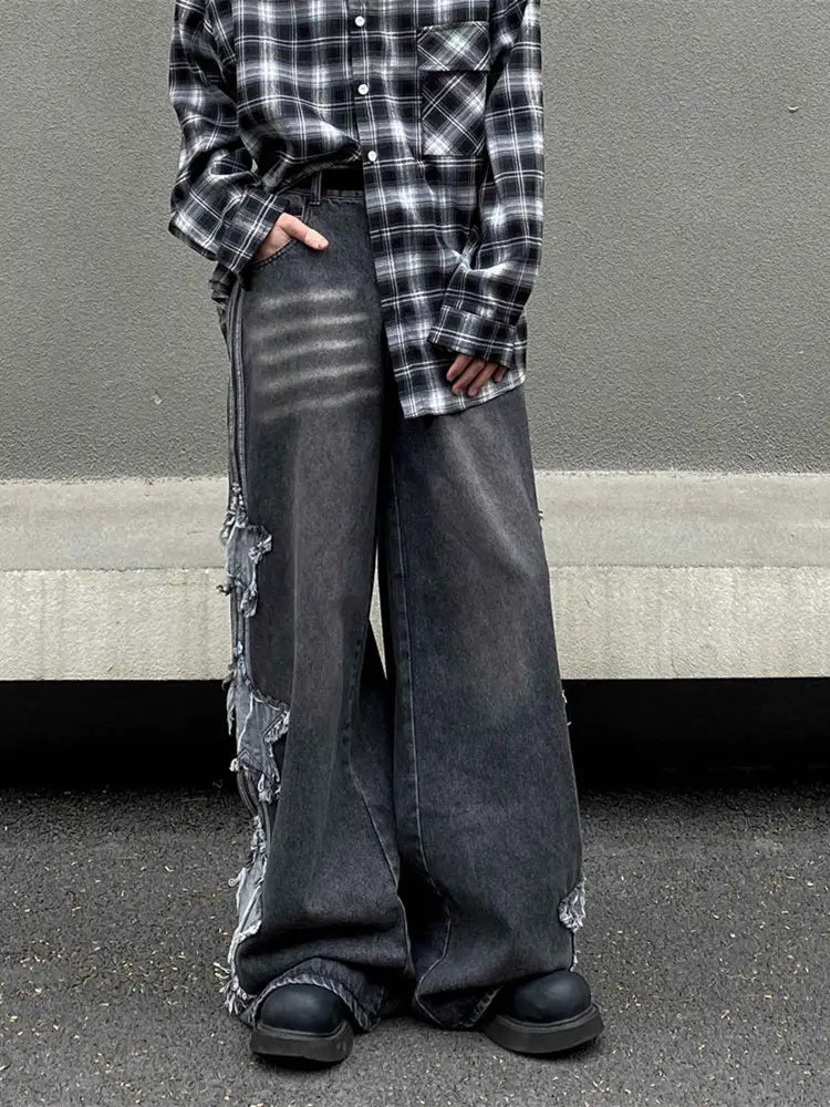 Jeans denim wide-leg gris foncé avec des panneaux latéraux effilochés et déchirés dans un style y2k baggy.