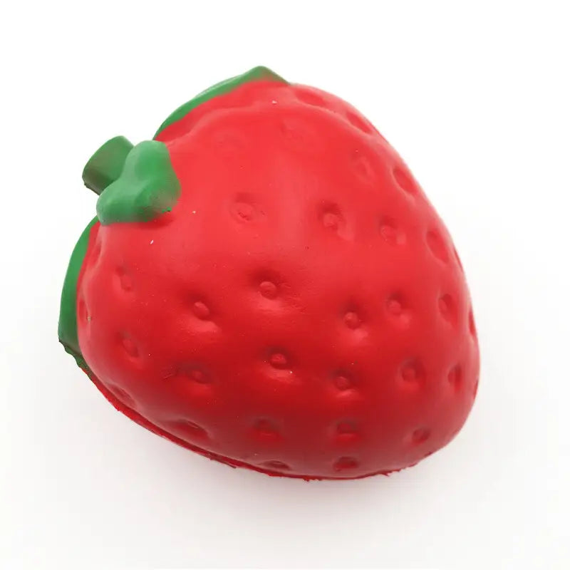 Juguete antiestrés de fresa roja con forma de fresa, que se eleva lentamente y es blandamente esponjoso, con una parte superior de hojas verdes y superficie texturizada.