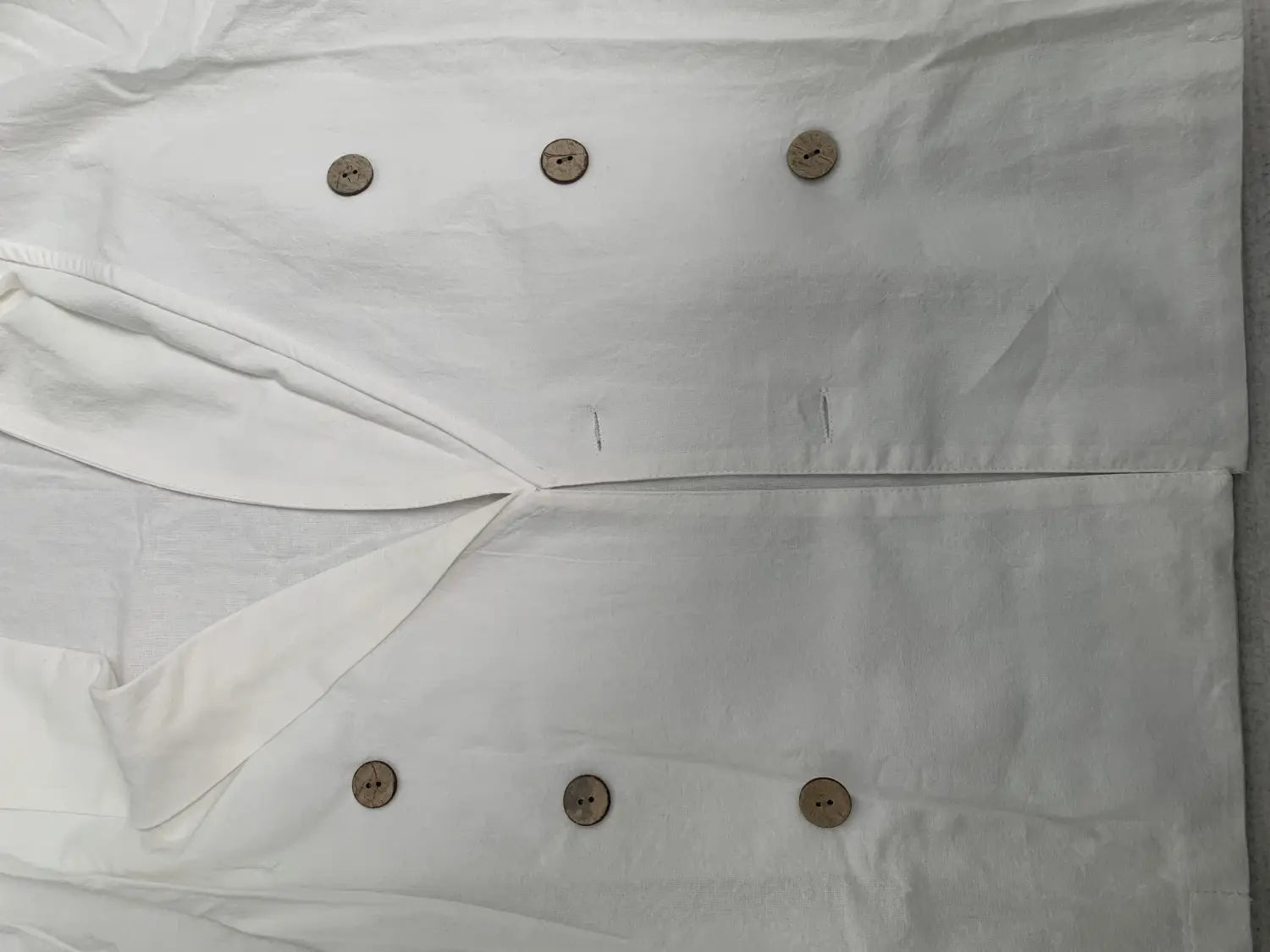 Men long sleeve white linen shirt with a mandarin collar and six round light brown wooden buttons arranged in two rows for casual wear.