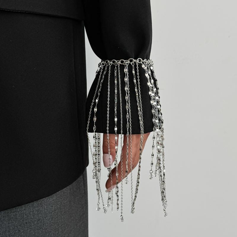 bracelet de manchette à franges en chaîne d'argent pour femmes, avec maillons en cascade et charmes métalliques suspendus dans un motif de charme à gland géométrique.