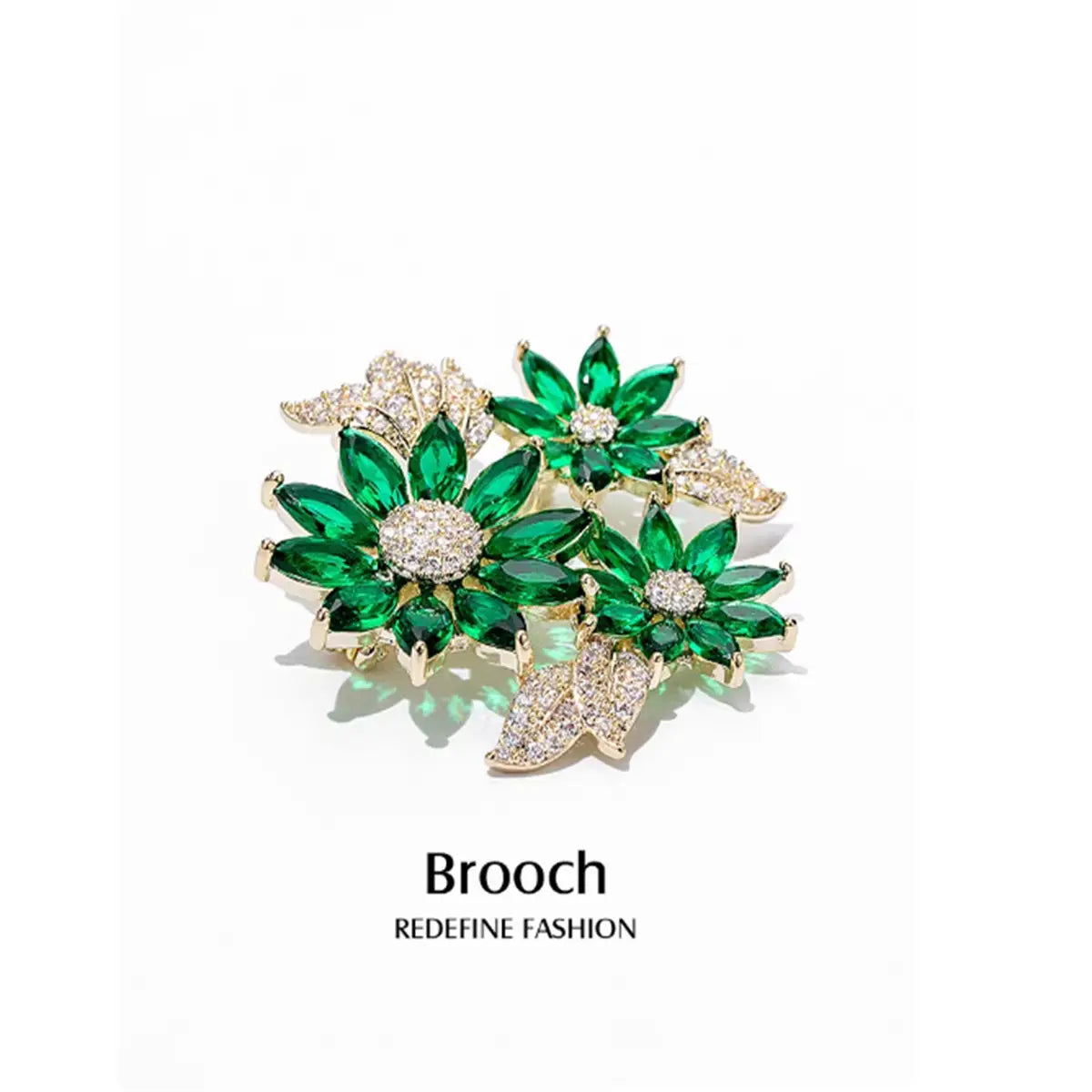 A sparkling green and gold floral brooch pin adorned with emerald-cut crystals and pave-set diamonds.
