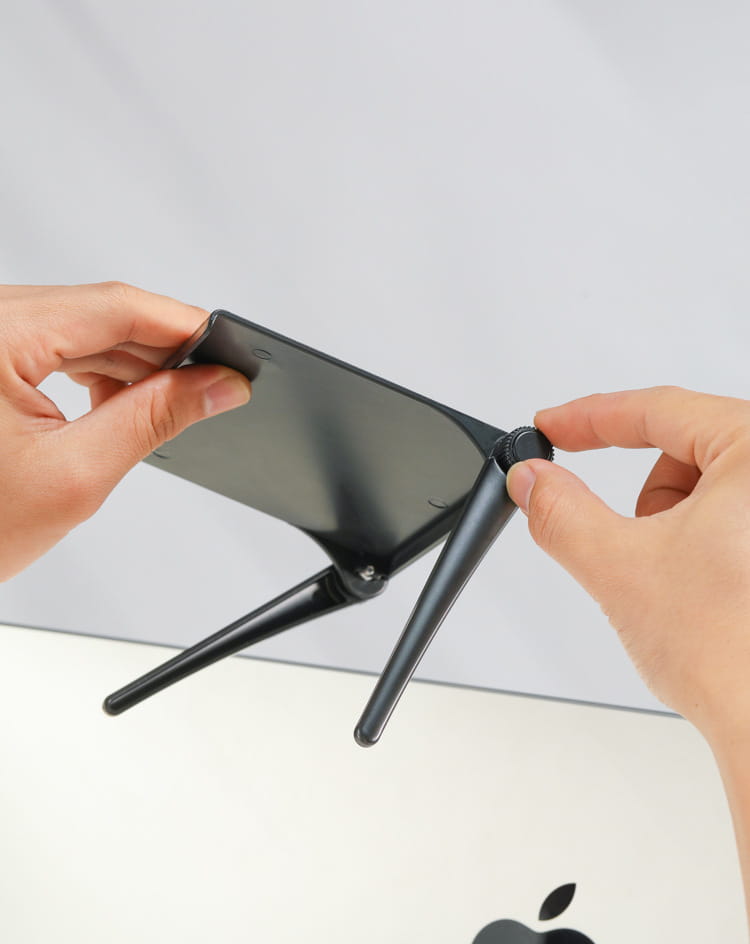 Black foldable phone stand with adjustable legs and central knob for height control designed as an adjustable screen top storage shelf monitor stand.
