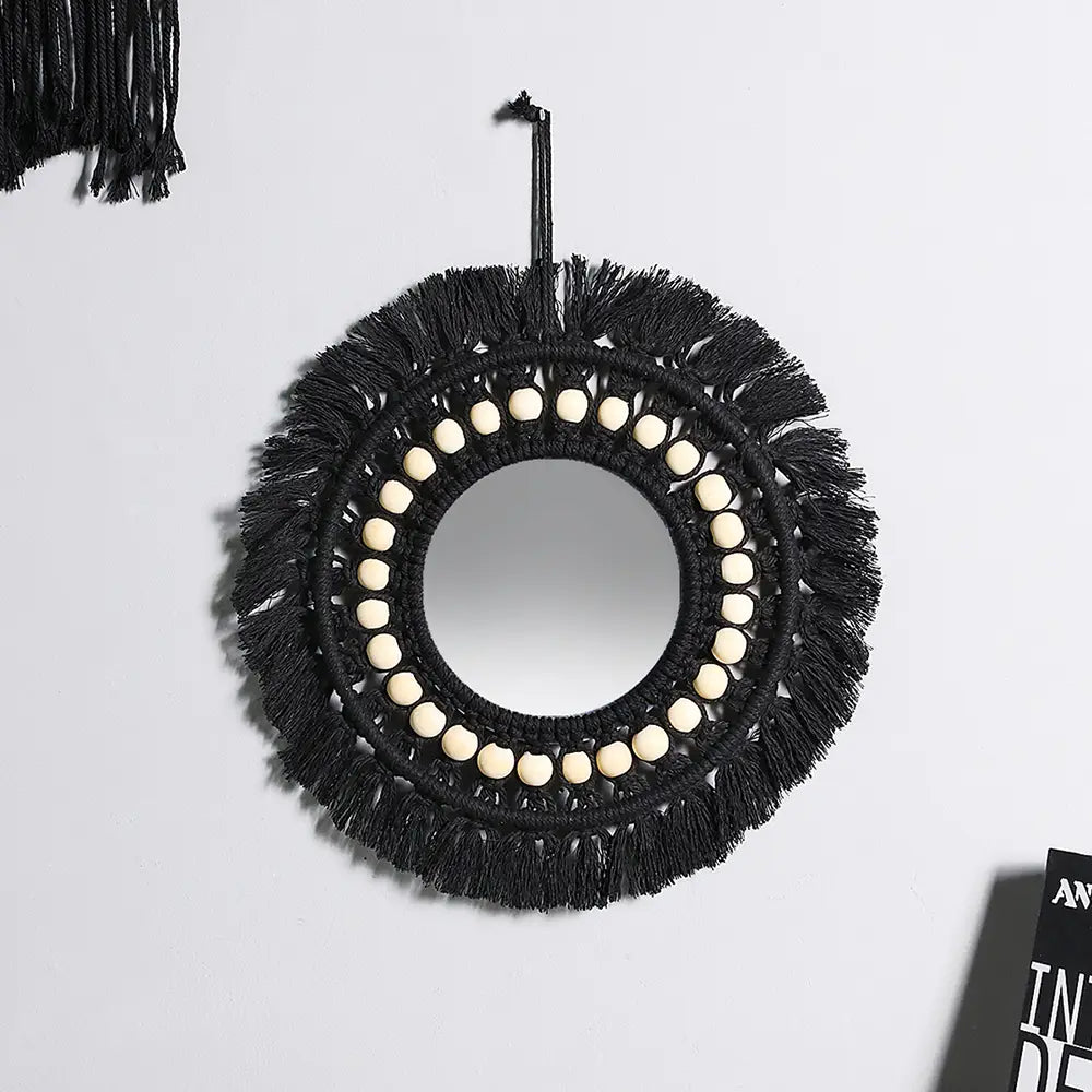 Black macrame-fringed round wall mirror with cream-colored wooden beads decorative mirror for boho home decor.