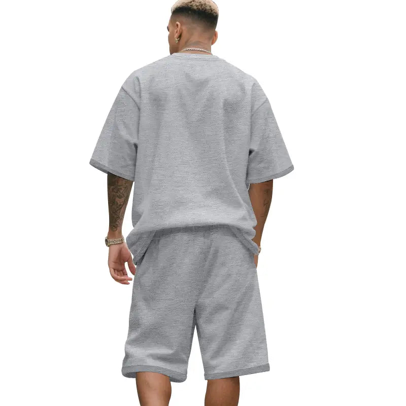 Conjunto veraniego de dos piezas para hombre de algodón gris jaspeado, con camiseta casual y conjunto de pantalones cortos de ajuste relajado y puños enrollados.