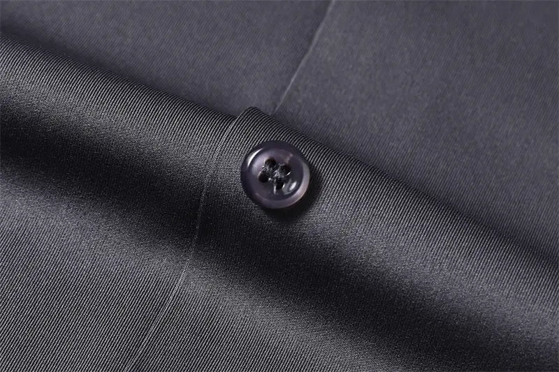 Botón negro con cuatro orificios incorporado en tejido texturizado gris oscuro de la camisa de vestir para hombre sin arrugas.